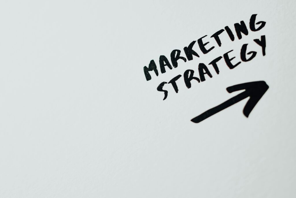 Close-up of handwritten 'Marketing Strategy' text with an arrow on white background.