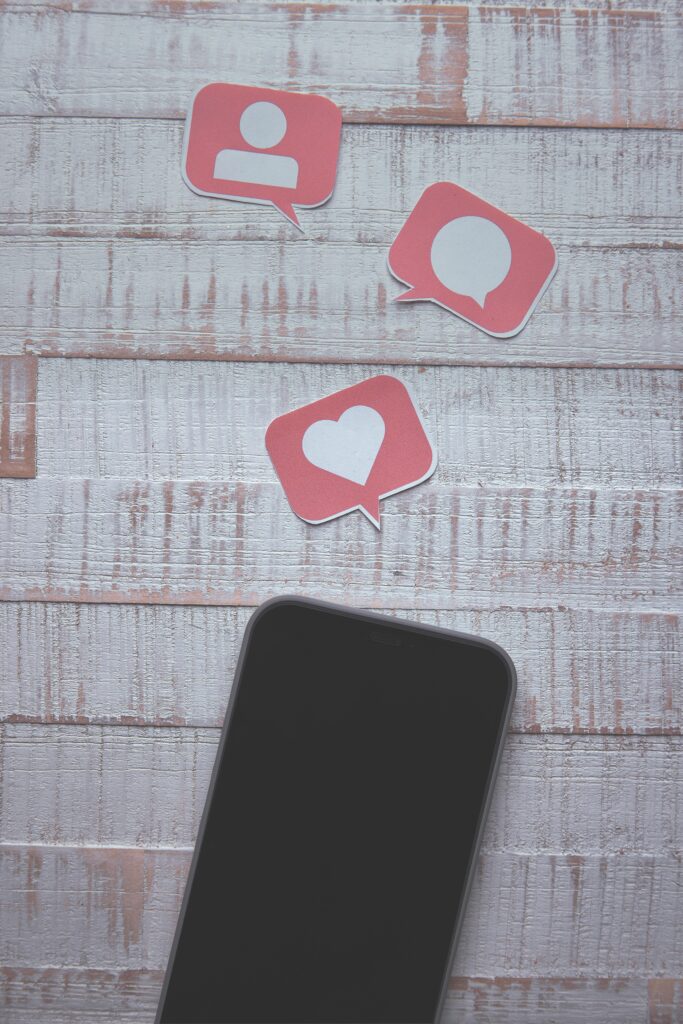 Top-down view of a smartphone with social media icons on wooden background.