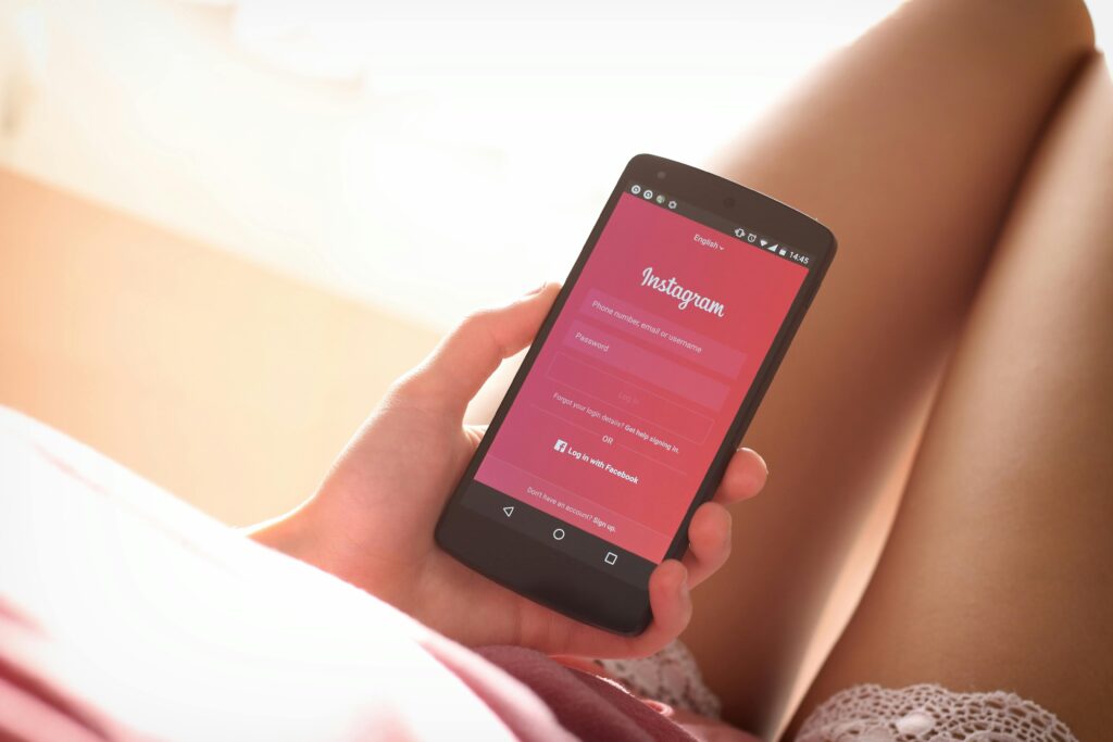 Woman holding a smartphone with Instagram login screen while relaxing indoors.