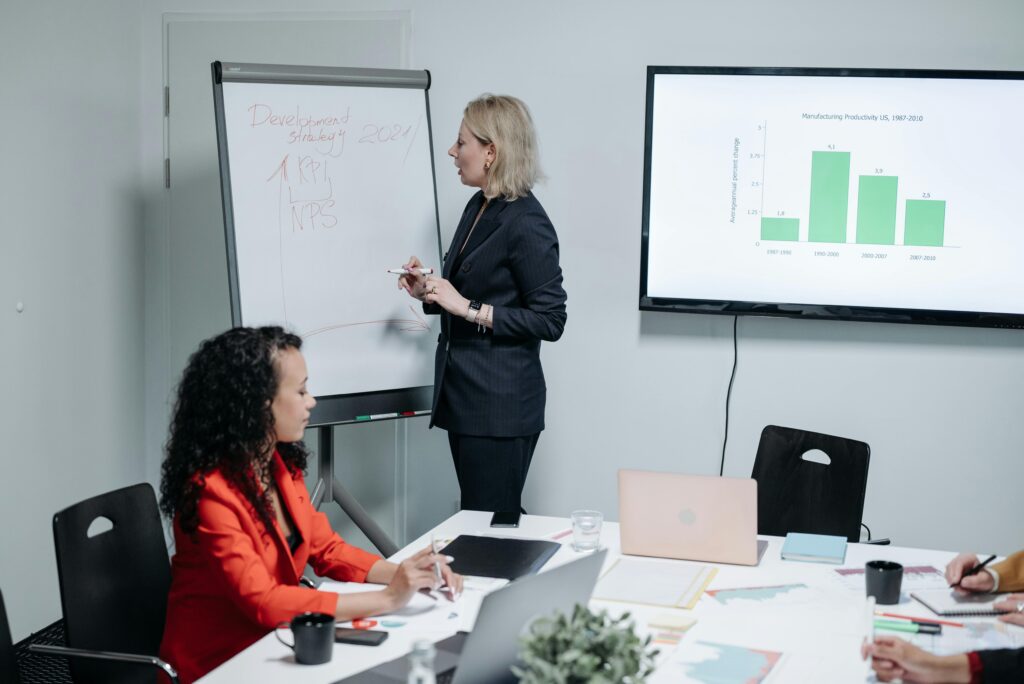 Businesswomen discussing strategy in modern meeting room with charts and analysis.