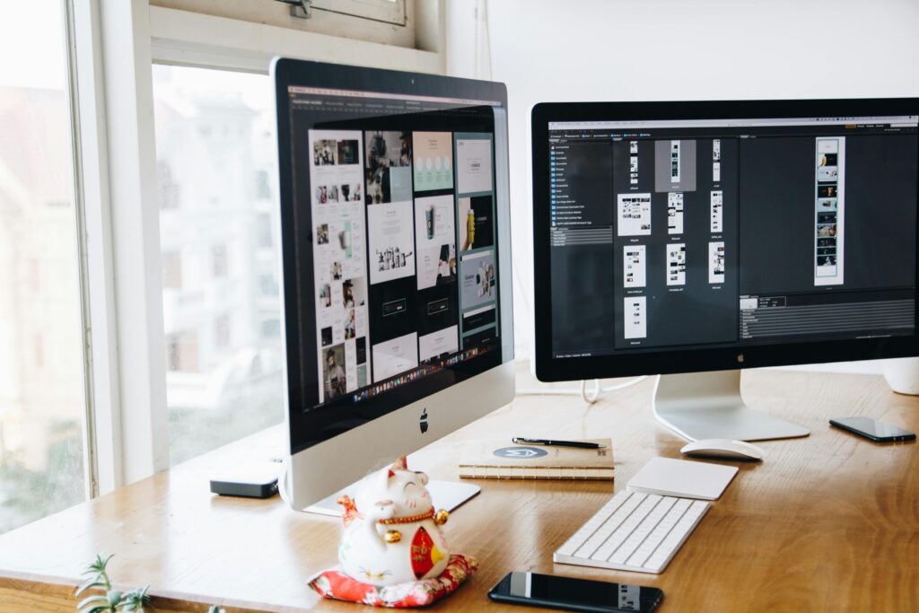 A sleek modern office setup featuring dual monitors, Apple devices, and creative decor in an indoor workspace.